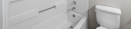 a white bathroom with a white toilet and a bath tub