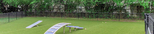 a large grassy area with a fence and lounge chairs