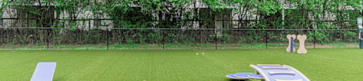 a large grassy field with a fence in the background and a row of trees in the