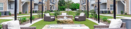 an outdoor lounge area with chairs and a fire pit in front of an apartment complex