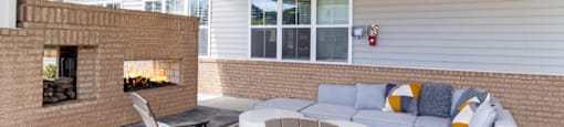 a patio with a couch and chairs and a fireplace