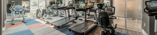 a gym with weights and cardio equipment on the floor and a glass door