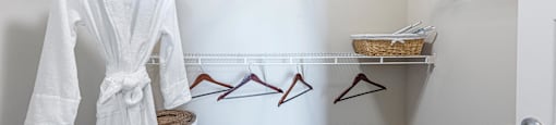 A white bathroom with a white robe hanging on the rack.