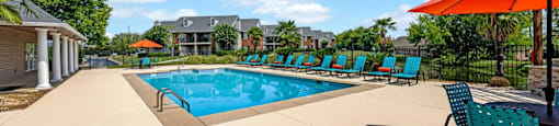 our resort style swimming pool is surrounded by lounge chairs and an umbrella