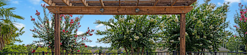 a patio with a stone fireplace and a wooden pergola