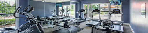 a gym with treadmills and other exercise equipment and windows