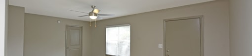 an empty living room with a ceiling fan