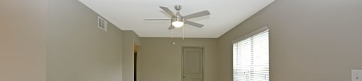 an empty living room with a ceiling fan