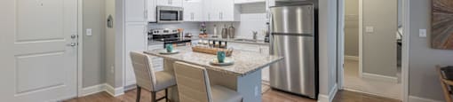 a kitchen with a large island and a stainless steel refrigerator