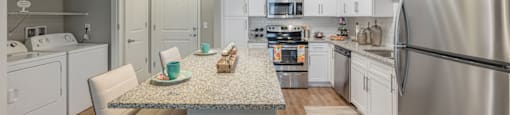 an open kitchen with stainless steel appliances and a granite counter top