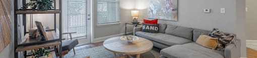 a living room with a gray couch and a ceiling fan