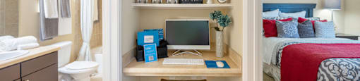a bedroom with a desk with a computer on it and a bed