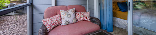 a covered porch with a pink chair and a glass coffee table