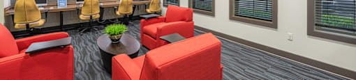 a lounge area with red chairs and a desk with a computer