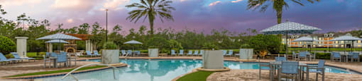 a swimming pool with tables and chairs and palm trees