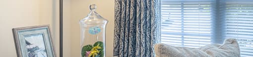 a corner of a room with a window and a table with a vase with