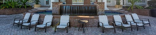 a patio with chairs and a fountain in front of a house