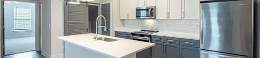 A modern kitchen with a white island and stainless steel appliances.