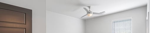an empty bedroom with a ceiling fan and a window