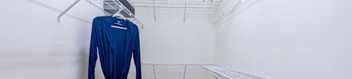 a walk in closet with a dress hangar and a trash can
