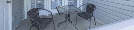 a covered porch with two chairs and a table