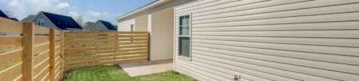 A backyard with a wooden fence and a green lawn.
