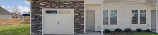 A two-story house with a garage on the first floor at Allen Ridge Townhomes in Greenville, NC.