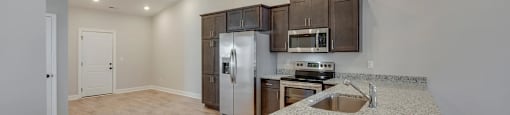 A kitchen with a granite counter top and wooden cabinets.