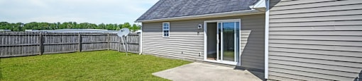 A house with a grey siding and a black roof with a small window and a door.