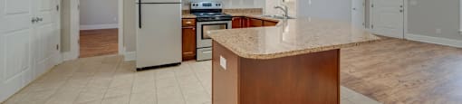 A kitchen with a refrigerator, microwave, oven, and sink.