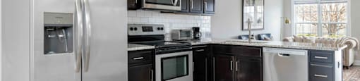 A modern kitchen with a stainless steel refrigerator and black cabinets.
