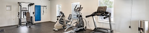 the gym has plenty of exercise equipment and a tv