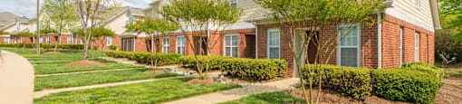 A row of houses with green lawns and trees in front at Haven at Research Triangle Park apartments in Durham, NC.