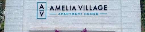 A white sign for at Amelia Village apartments in Clayton, NC.