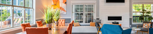 a living and dining room area with a large wooden table and orange and blue chairs