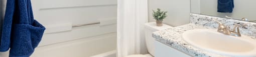 a bathroom with a white shower curtain and a white toilet next to a sink with a blue