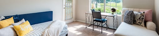 a bedroom with a bed and a chair in front of a window