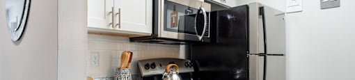 a kitchen with white cabinets and black appliances