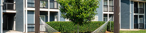 a hammock sits in the grass in front of an apartment building