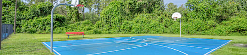 A blue basketball court with a red bench and a basketball hoop.