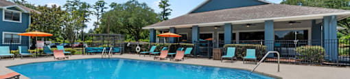 A large swimming pool with lounge chairs and a building in the background.
