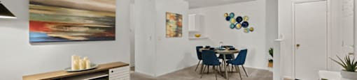 A living room with a blue couch and a painting on the wall.
