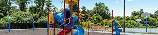 A playground with a blue and yellow structure and a red slide.