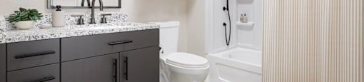 A bathroom with a white toilet and a white shower curtain at Boardwalk at Research Park apartments in Huntsville, AL.
