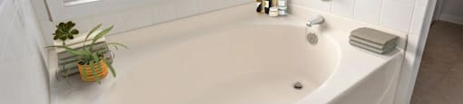 A white bathroom with a tub, towel, and window.