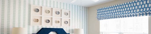 A bedroom with a bed, nightstands, and a window with a blue and white striped valance.