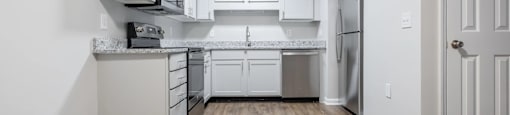 A kitchen with white cabinets and a wooden floor.