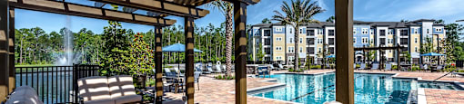 a resort style pool with lounge chairs and a pergola