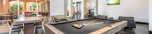 a pool table in the clubhouse of a home with a bar and a dining area