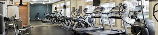 a gym with cardio equipment and weights on the floor